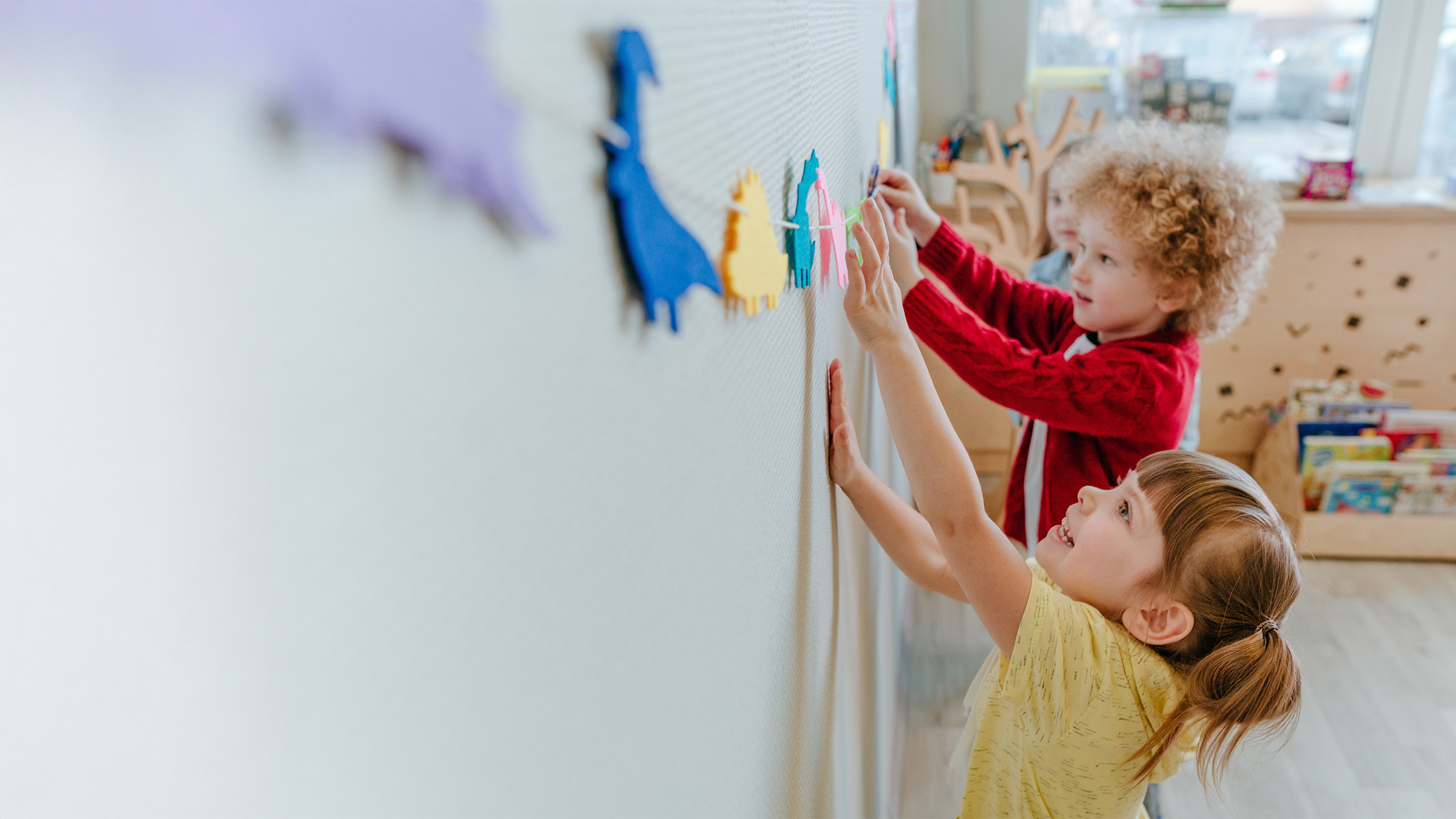 Preschool students playing in kindergarten with color dinosaur figures